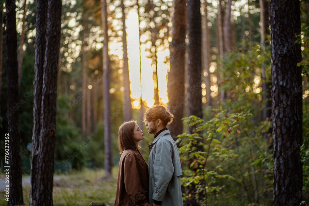 couple in love in the forest at sunset on a date hugging in a coat in the summer. Cinematic love story couple in love in the forest at sunset on a date hugging in a coat in the summer. Cinematic love story