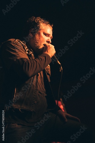 Vertical shot of a man singing into a microphone on the black background