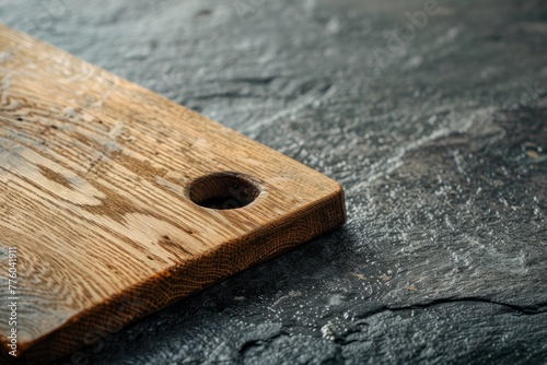 A handcrafted wooden cutting board with a hole placed on a stone surface, highlighting artisanal craftsmanship