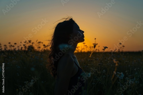 A woman stands in a field at sunset, silhouetted against the setting sun, practicing deep CJNP © Ilia Nesolenyi