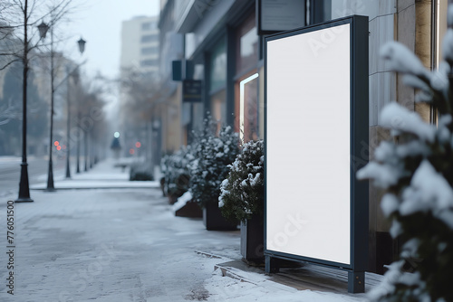A white sign stands on the side of a street covered in snow. The sign is propped up against a snowy background, indicating important information to passing pedestrians or vehicles. Perfect for mockups