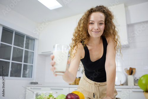 young woman smiling and holding fresh milk in the kitchen