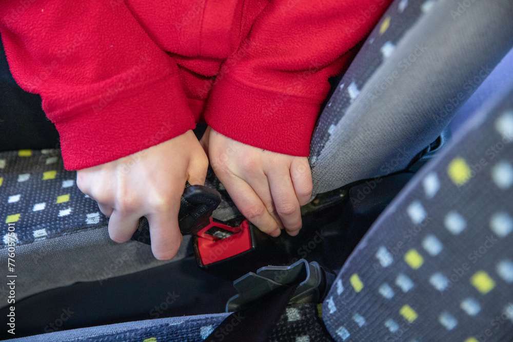 Gros plan d'un enfant attachant sa ceinture de sécurité dans un bus - obrazy, fototapety, plakaty 