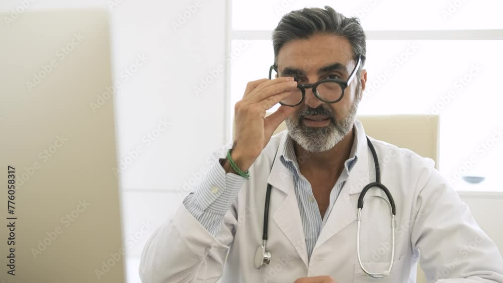 Confident male doctor talking and looking at camera in clinic Confident male doctor talking and looking at camera in clinic