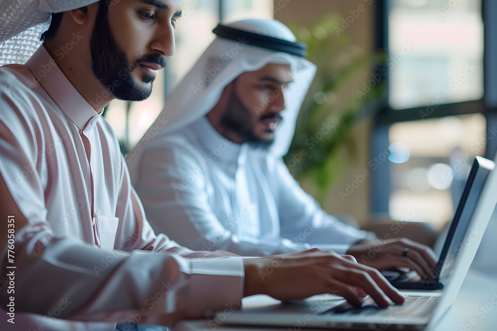 Two arabian man working in an office typing on a laptop