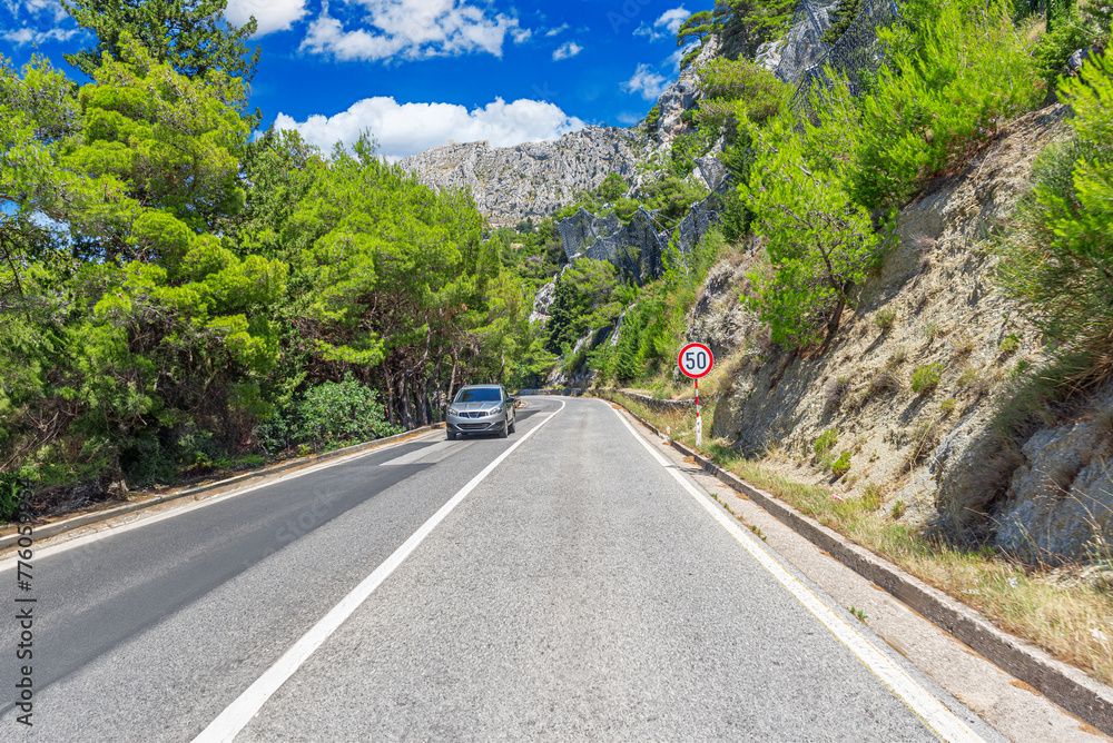 Fototapeta premium Country road with rocky mountains in the background.