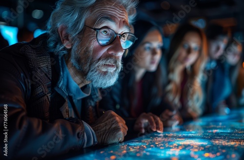 A group of people gathered around an interactive table, looking at the screen and discussing the digital materials in a low light environment. The scene captures their focused expressions as they enga photo