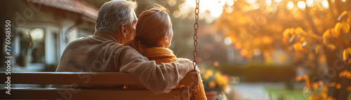 Elderly father with arms around daughter sits on swing in garden, sharing cherished moments and love. photo