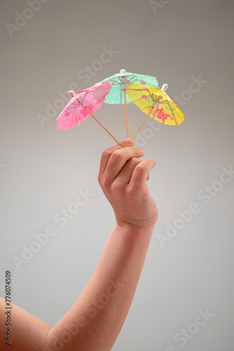 Person holding three small umbrellas made of wood and plant twigs