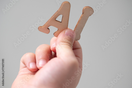 a person is holding wooden letters AI in their hand
