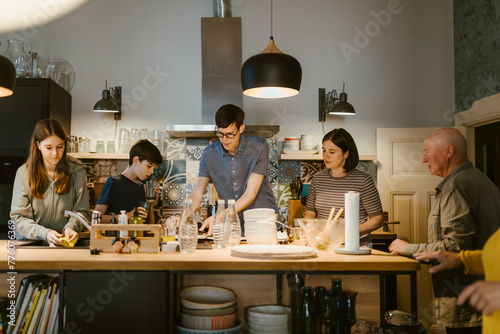 Multi-generation family helping each other in cleaning kitchen after dinner at home photo
