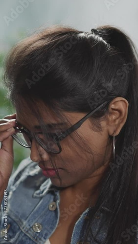Indian woman with ponytail puts on glasses to read book photo