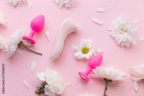 Top view Different set sex toys for woman on pink background with flowers. Sexshop advertising banner