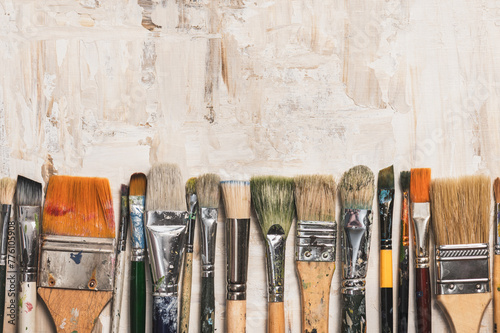 Fototapeta Naklejka Na Ścianę i Meble -  Row of old vintage paint brushes on a beige primed canvas background.Creativity concept.