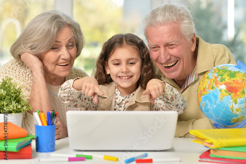 grandparents and little girl using laptop on the table