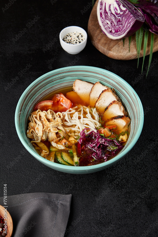Chinese soup with noodles, chicken meat and vegetables in ceramic bowl on dark background. Asian cold soup in korean style and pick up noodles. Chinese cuisine in modern style.. Chinese soup with noodles, chicken meat and vegetables in ceramic bowl on dark background. Asian cold soup in korean style and pick up noodles. Chinese cuisine in modern style..