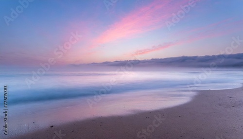 Beach in pink tones with fog coming down on horizon