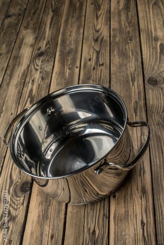 A stainless steel casserole on a old rough wooden table. Selective focus.