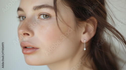 Side view of a woman with casual hair  subtle makeup  and a pearl earring gazing away thoughtfully