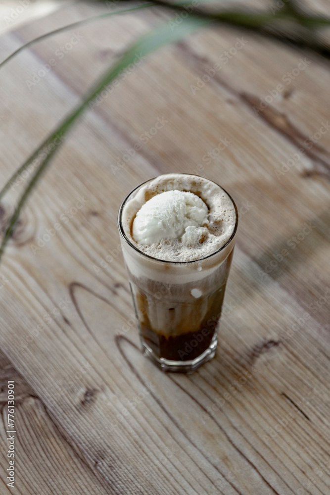 Iced coffee with whipped cream in a glass on a wooden table Iced coffee with whipped cream in a glass on a wooden table