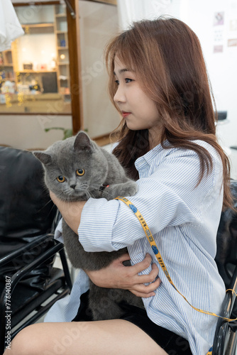 Stylish Young Vietnamese Woman in Striped Shirt Embracing Cat Poses at Coffee Shop - SEO-Friendly Title