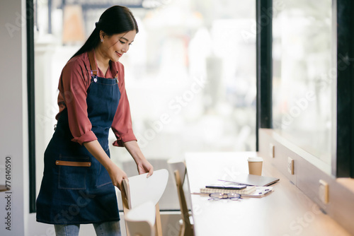 A woman in a blue apron is cleaning a table