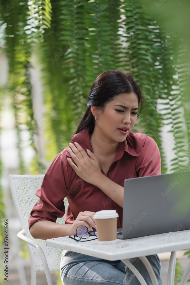 A woman in a red shirt is sitting at a table with a laptop and a cup of coffee A woman in a red shirt is sitting at a table with a laptop and a cup of coffee