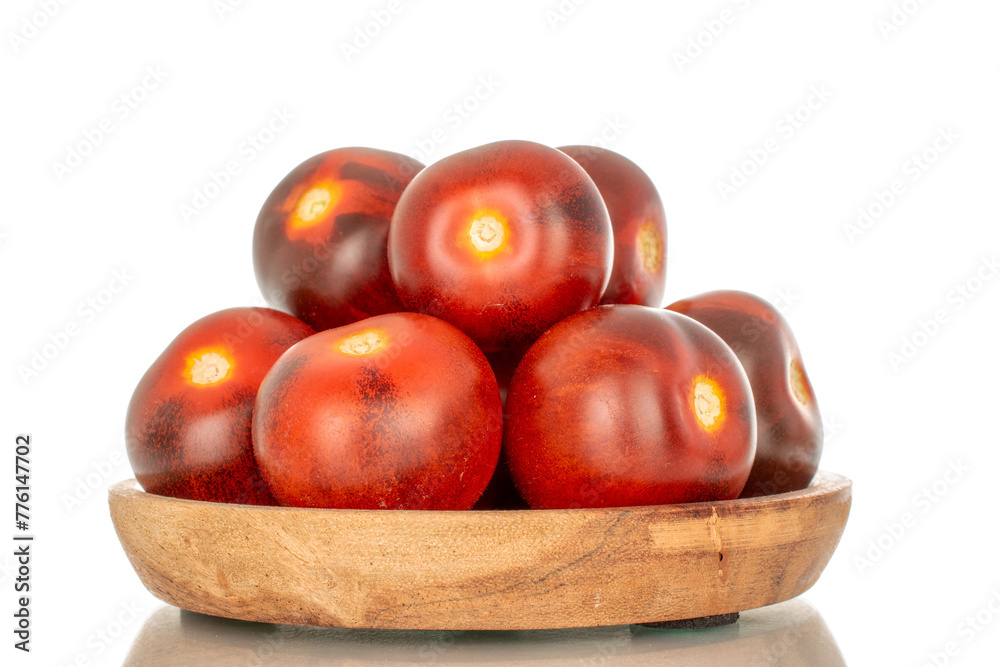 Several ripe black cherry tomatoes on a wooden saucer, macro, isolated on white background. Several ripe black cherry tomatoes on a wooden saucer, macro, isolated on white background.