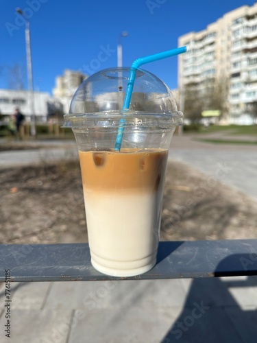 Latte in a transparent plastic cup and with a straw