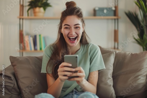 happy excited young woman holding a smartphone while sitting on a sofa at home