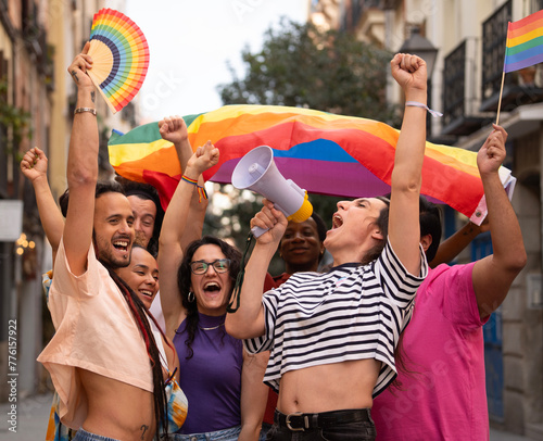 Group of LGBTQ people are holding rainbow flags and a megaphone during MADO party chueca pride gay day photo