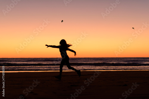 woman silhouette jumping in the beach before sunrise
