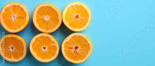  A collection of oranges, halved, on a blue background; one orange hemisphere next to another
