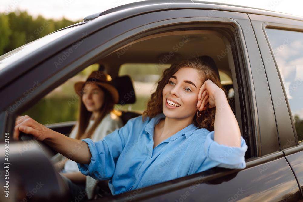 Beautiful female friends in the car enjoy a car trip together. Lifestyle, travel, tourism, nature, active life.