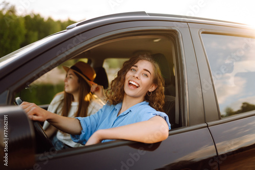 Beautiful female friends in the car enjoy a car trip together. Lifestyle, travel, tourism, nature, active life. © maxbelchenko