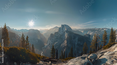 A panoramic view of a mountain range with a sun shining on the peaks