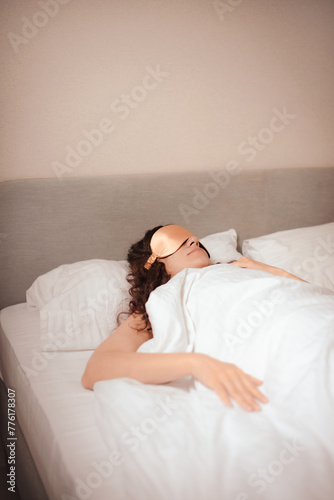 young woman in beige silk sleep mask sleep in bed in hotel. Improving sleep quality