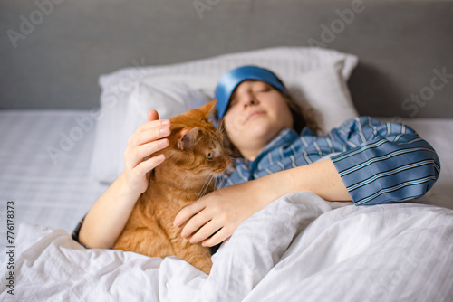 red cat came to wake up woman in bed in morning in bedroom
