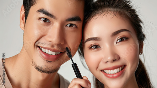 Smiling Asian couple close-up  woman holding mascara beauty product.