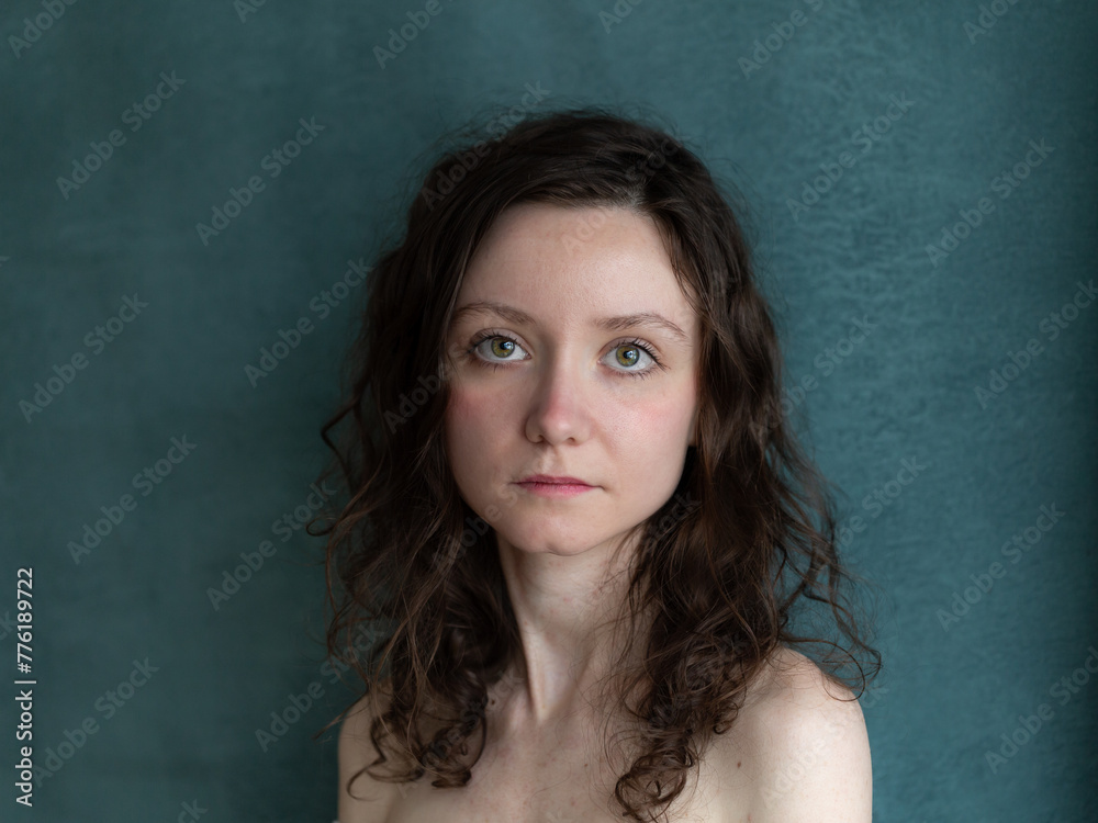 Horizontal closeup portrait pretty brunette serious young woman bare shoulders blue background Horizontal closeup portrait pretty brunette serious young woman bare shoulders blue background