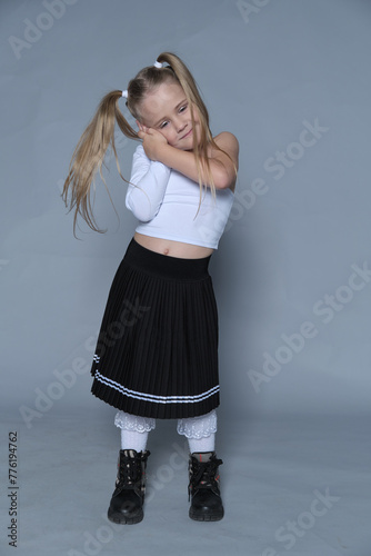Girl in white top and pleated skirt exudes charm, her joyful expression showcasing the happiness of carefree youth.