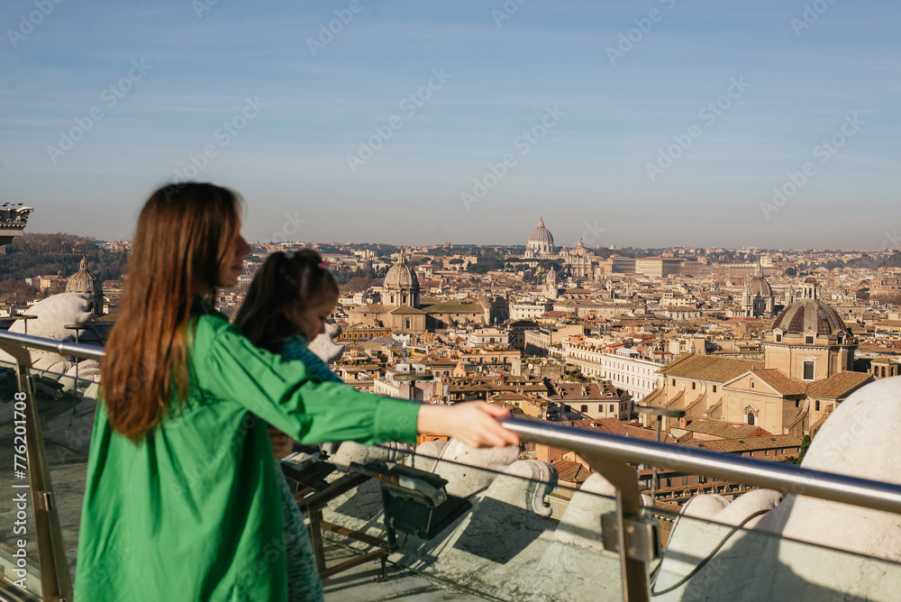 young happy mom and daughter on the rooftop of the city in rome.