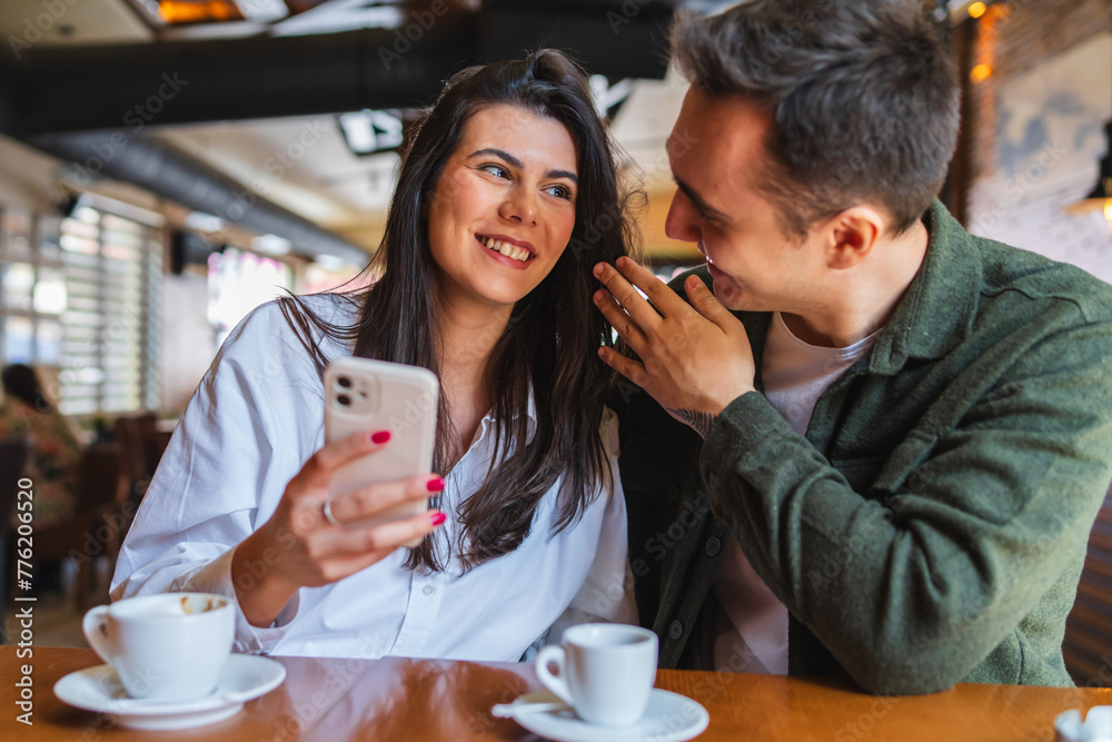A young couple boyfriend and girlfriend or friends are drinking coffee having fun and taking selfies in cafe or restaurant A young couple boyfriend and girlfriend or friends are drinking coffee having fun and taking selfies in cafe or restaurant