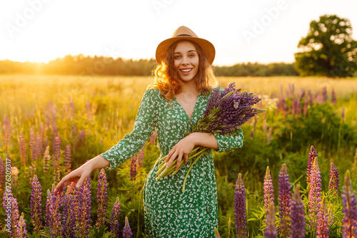 Portrait of young woman holding bouquet of lavender flowers walking in summer meadow. Nature, vacation, relax and lifestyle. Collection of medicinal herbs © maxbelchenko