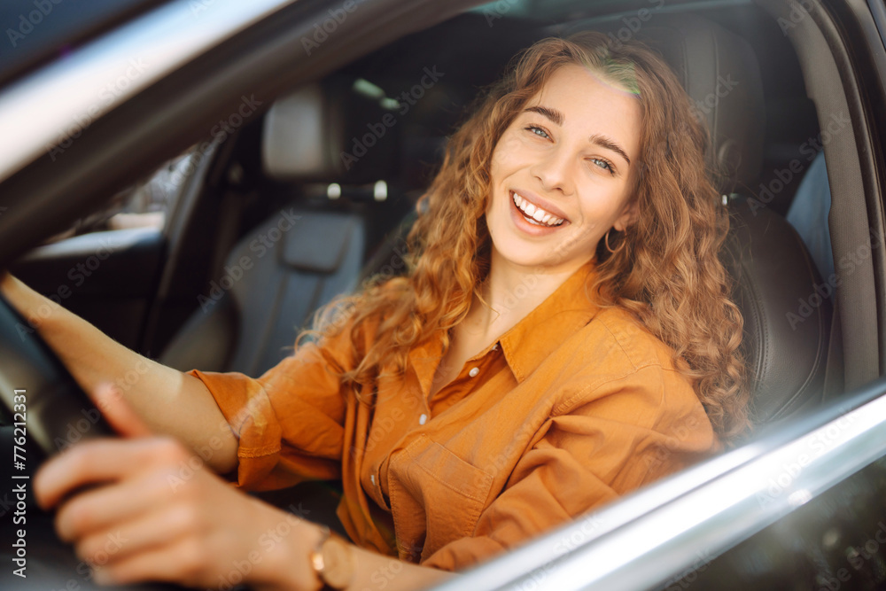 Portrait of young woman is driving a car and smiling. Automobile travel. Sharing a car. Lifestyle concept.