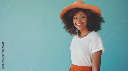 Mulher fashion usando uma camiseta branca e um chapeu e saia terra cota no fundo azul claro  photo