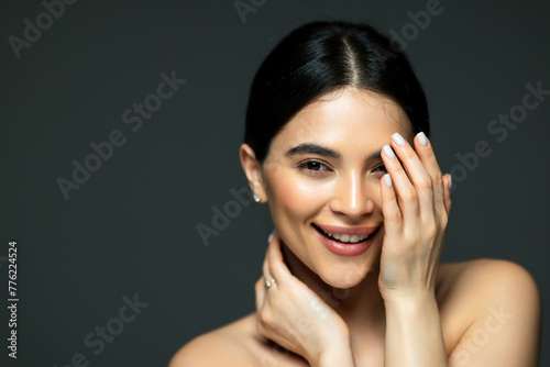 Close up beauty portrait of woman applying face cream and looking away isolated over white background