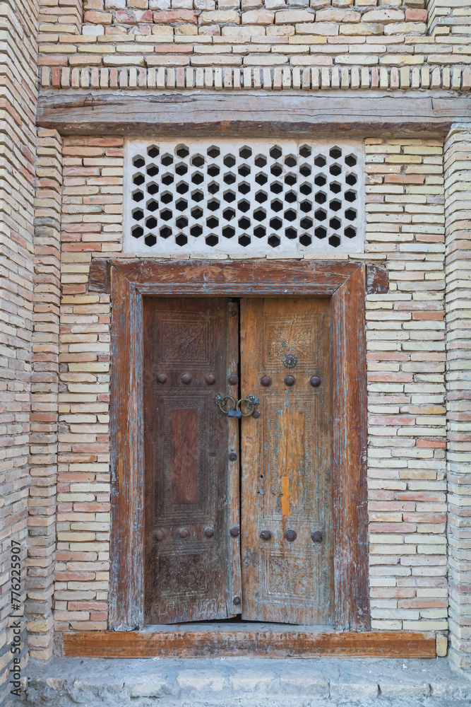 Old wooden door in a brick building in Bukhara.