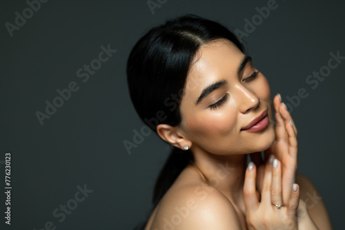 Beautiful woman face closeup portrait hands on skin isolated on dark background