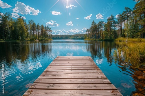 Traditional Finnish and Scandinavian view. Beautiful lake on a summer day and an old rustic wooden dock or pier in Finland. Sun shining on forest and woods in blue sky photo